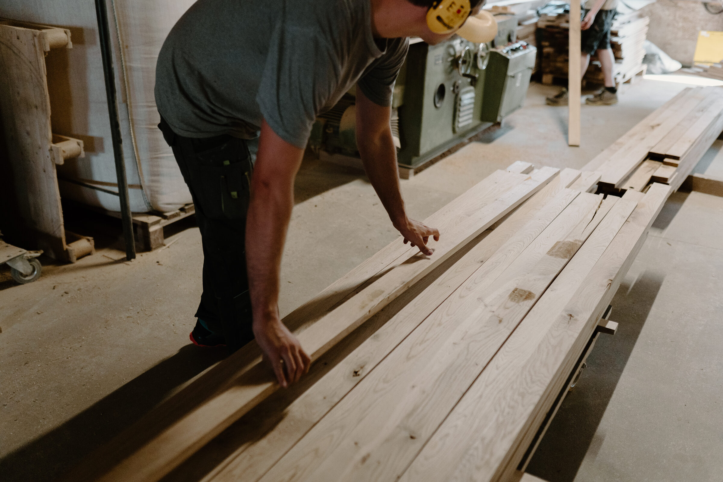 Craftsman inspecting timber boards on the workshop floor