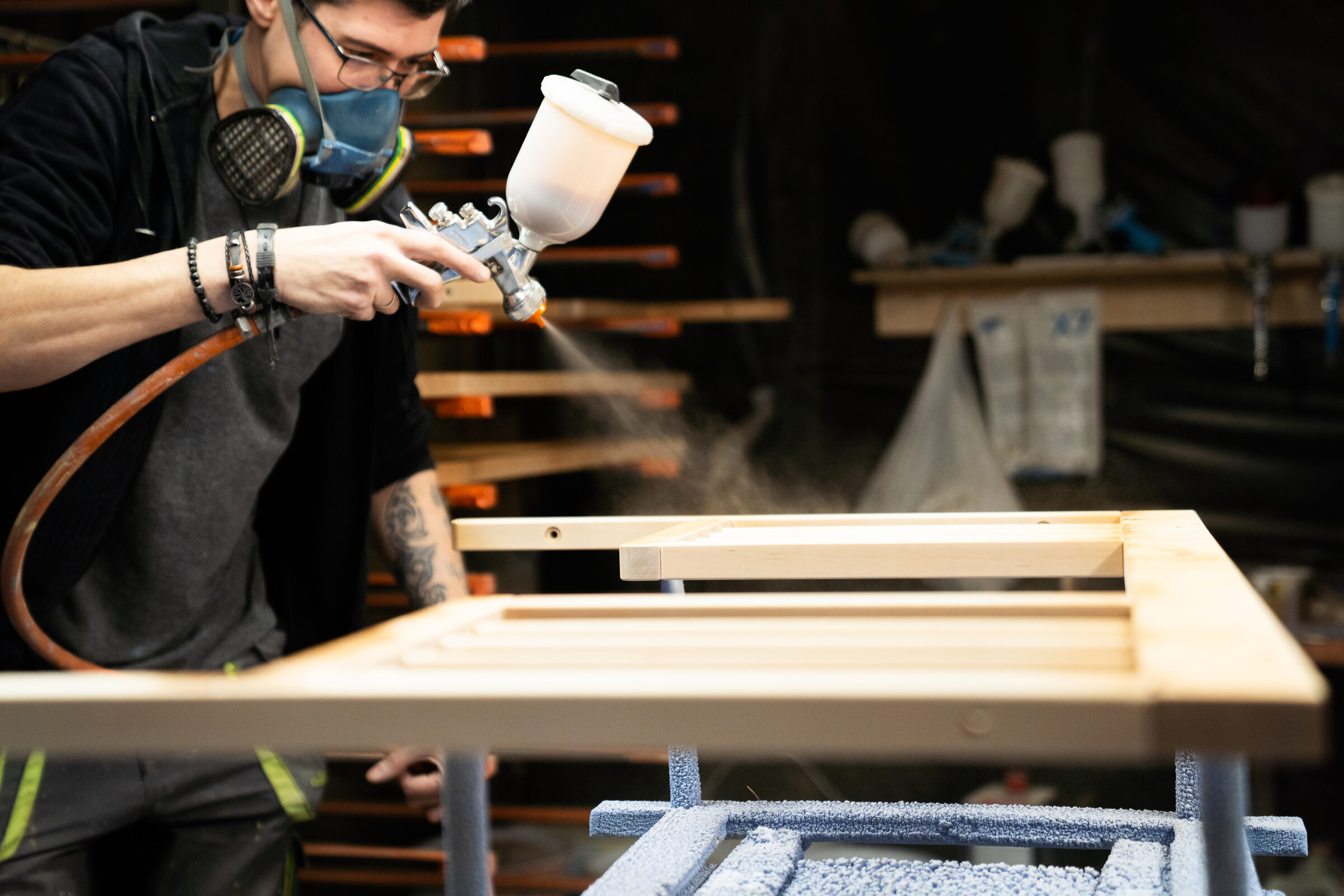 Craftsman applying spray finish to a frame